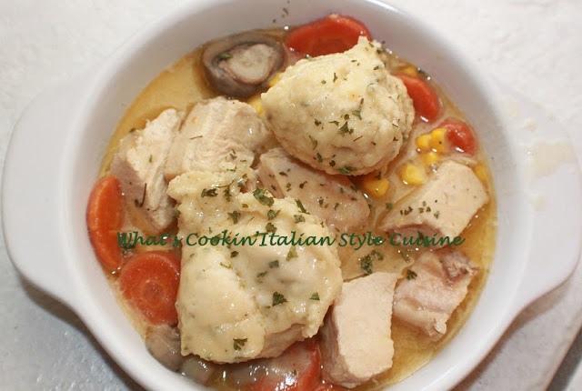 this is how to make chicken and dumplings with vegetables in a white plate swimming in a delicious broth dumpling sauce with herbs and spices, corn, carrots, loaded chicken and puffed up dumplings on top