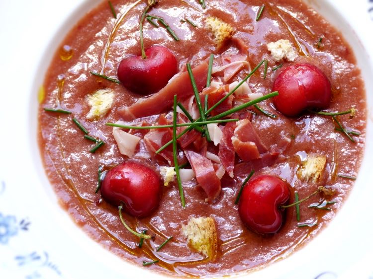 Plato hondo con gazpacho de cerezas, cebollino, pan, jamón. Receta saludable