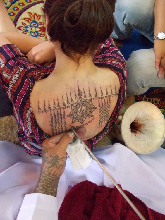 chica sometiendose a un tatuaje por monjes budistas