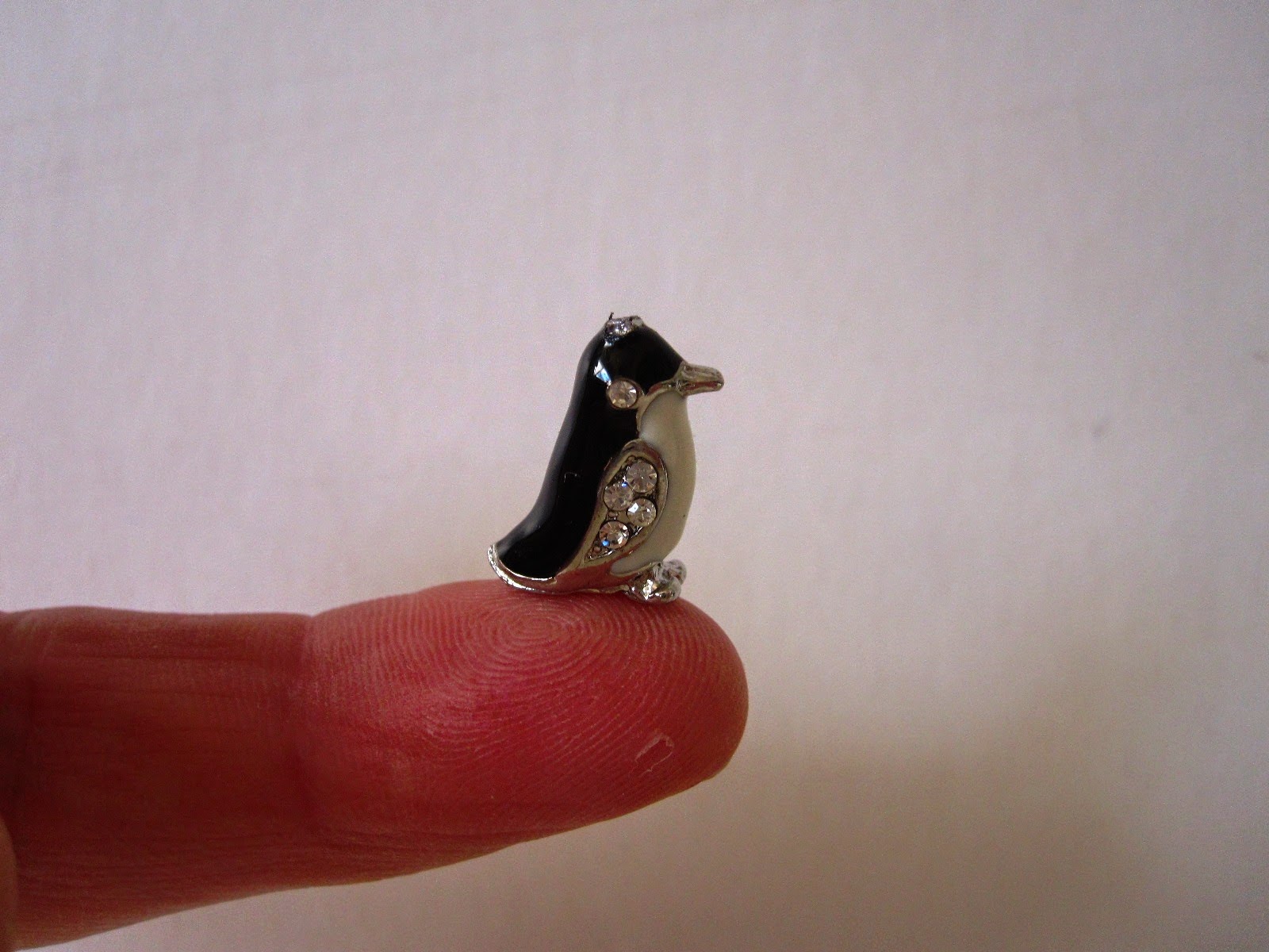 Small jewelled penguin charm, balanced on the end of a finger.