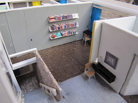 Interior of a 1/48-scale mid-century modern house playroom and study corner, with stone-edged stairs leading downwards.