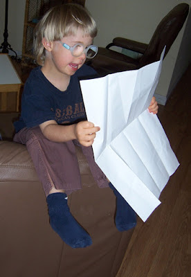Lisa's son as a child, sitting on the couch while holding up a piece of paper