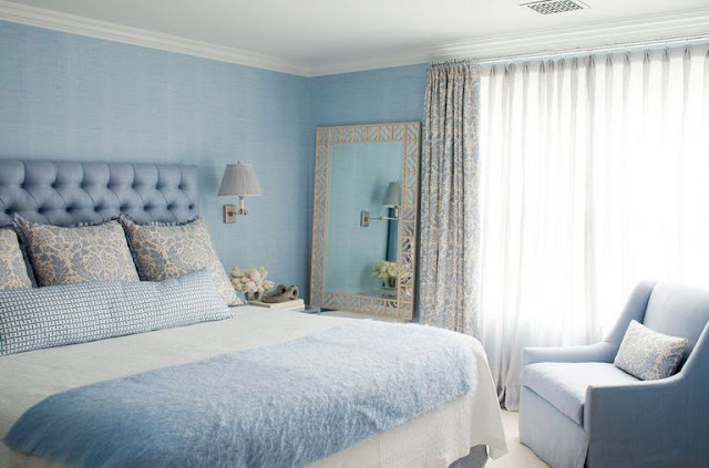Cornflower blue bedroom by Amanda Nisbet's with tufted headboard, arm chair, large mirror and floor length curtains