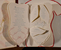 A book shaped like a torso, opened to show cut-out pages shaped like organs, bearing printed text.