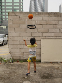 boy shooting a basketball into a bicycle tire hoop in Zhuhai, China