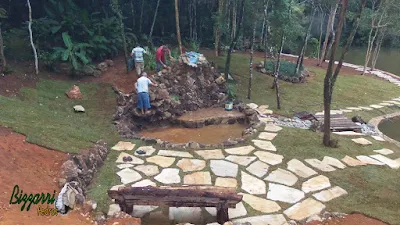 Execução do caminho com pedras em volta do lago com o muro de pedra em volta do lago, sendo caminho com pedra cacão de São Tomé com junta de grama.