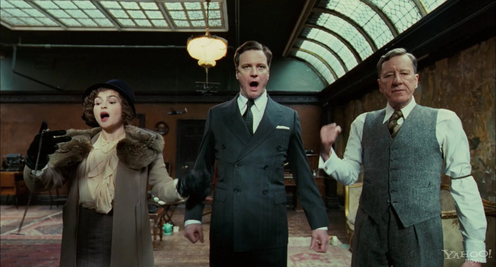Still image from The King's Speech showing Queen Elizabeth, Prince Albert, and Lionel Logue doing speech exercises