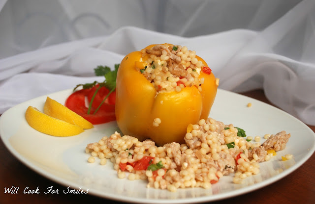yellow peppers stuffed with Couscous mixture on a plate with extra couscous and sliced limed 