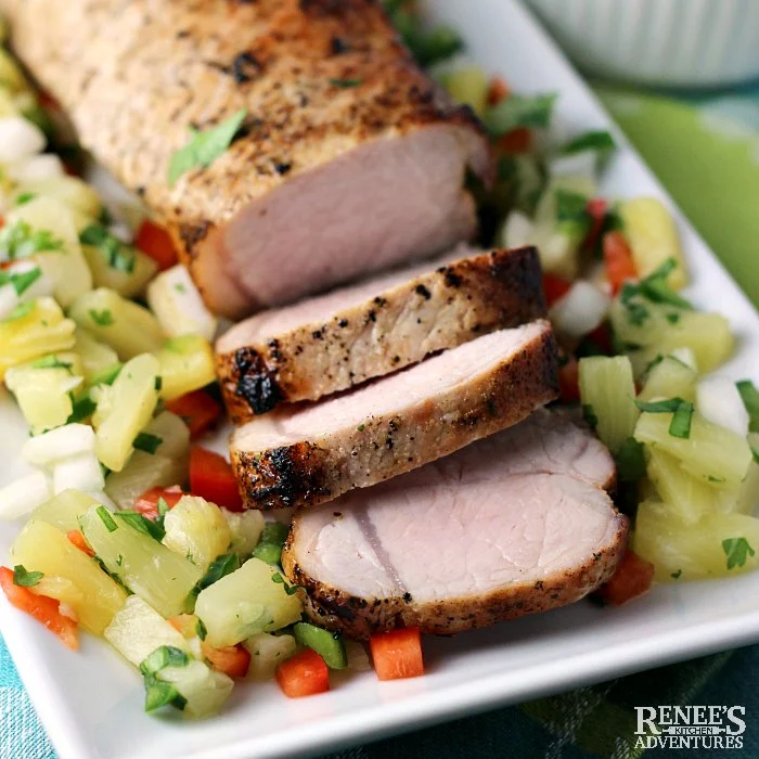 Grilled Pork Loin with Pineapple Salsa by Renee's Kitchen Adventures sitting on a white platter, sliced