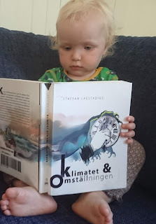 Lilla Eila tittar i boken Klimatet och Omställningen