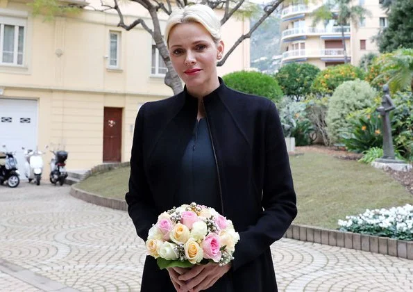 Princess Charlene wore Akris jumpsuit and Akris coat at Monaco Red Cross for Christmas gifts. Christian Dior erarrings