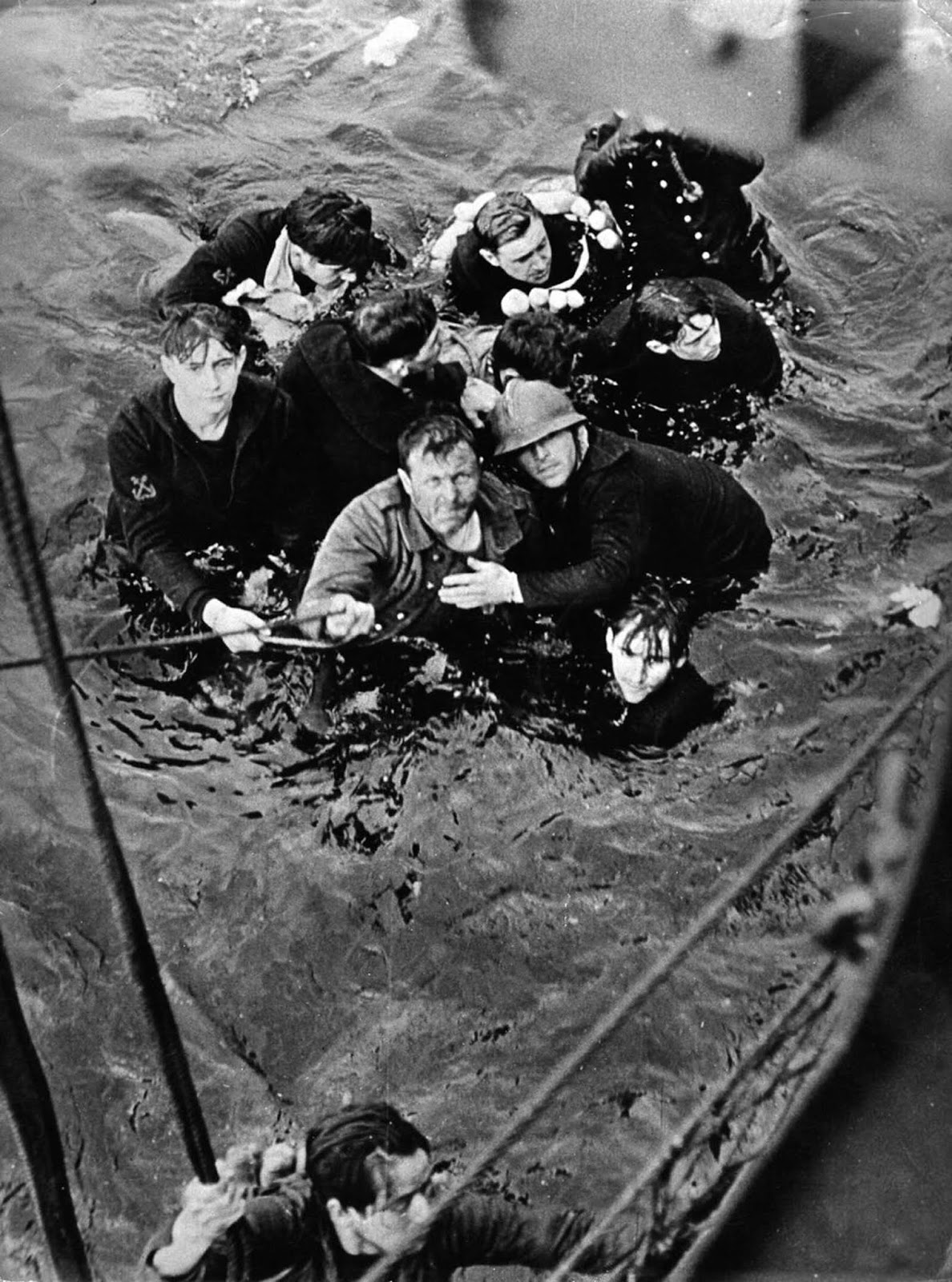 Crew members of the French destroyer Bourrasque, sunk by a mine at Dunkirk, are hauled aboard a British vessel from their sinking life raft.