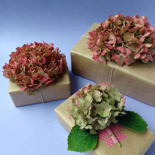 Get creative with your gift wrapping with these 10 DIY gift wrap ideas! three gifts decorated with hydrangea blooms
