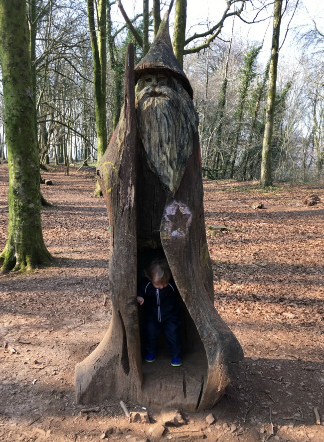 toddler exploring the inside of a hollow tree carved into the shape of a wizard