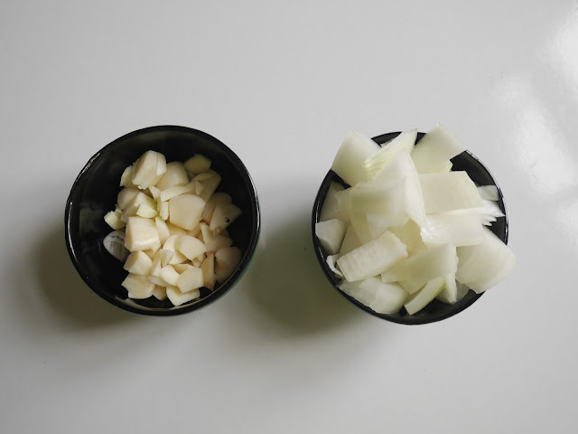 chopped garlic and white onion in black bowls on white table