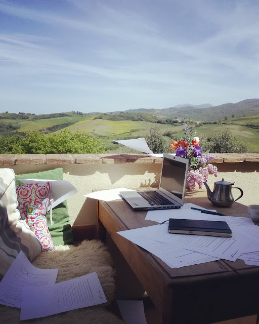 A computer on a table on a terrace with a view in Tuscany
