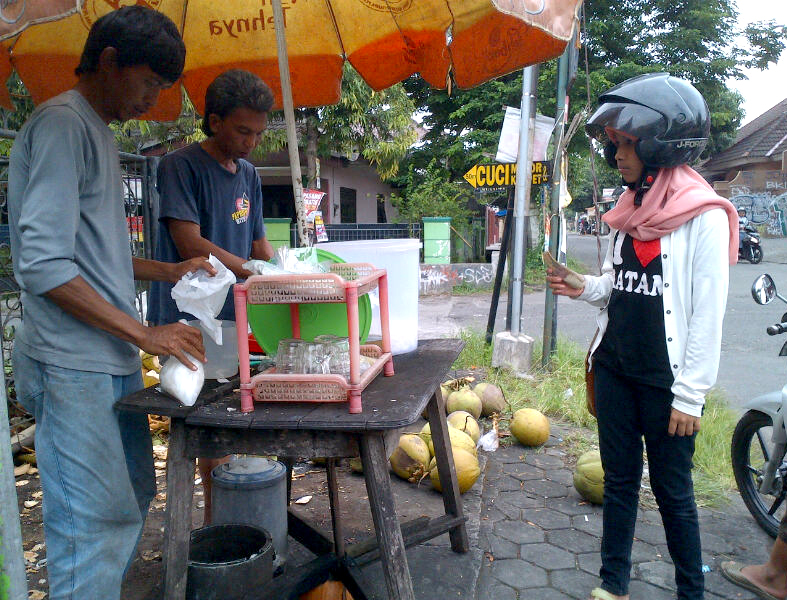 Penjual es kelapa muda saat melayani pembeli. Penjual es kelapa muda saat melayani pembeli.