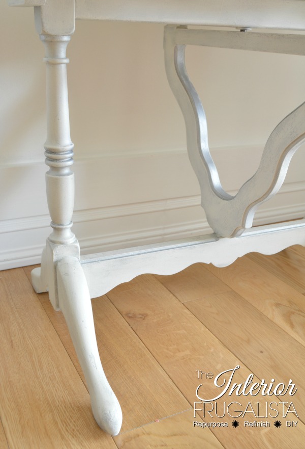 A scalloped tilt-top table painted white with chalk paint and metallic silver and pearl white gilding wax highlights.