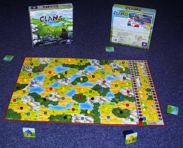 the board for Clans: a series of terrain types (yellow steppes, green forests, light green grasslands, and grey mountains, along with blue lakes). and the scoring track/epoch track on the right side of the board. Each terrain has one small wooden hut in one of five colours: red, green, yellow, black, and blue. There is a small wooden disk for each of these five colours sitting at the beginning of the scoring track, and each of the five spaces on the epoch track has a yellow wooden token. Around the board are the coloured hut tiles, with the green and yellow ones face up and the others face down. Behind the board is the box, showing the attractive and colourful design on the cover.