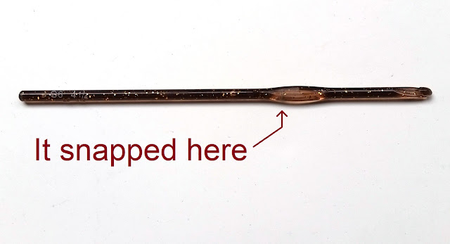 A brown glitter acrylic hook in one piece. The hook end is on the right. The left hand end has white lettering "G6 4½"  An arrow is pointing to the right end of the thumbrest where a find crack can be seen. The words next to the arrow say "It snapped here".