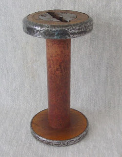 A wooden bobbin capped with metal at both ends
