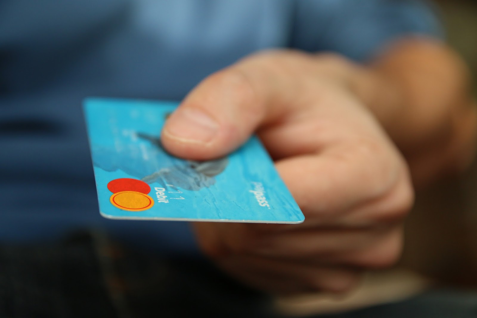 Debt management solutions - man's hand holding blue credit card