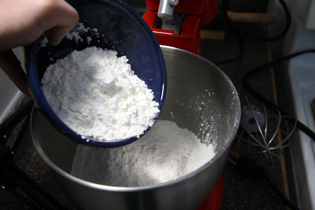 adding dry ingredients into the stand up mixer bowl
