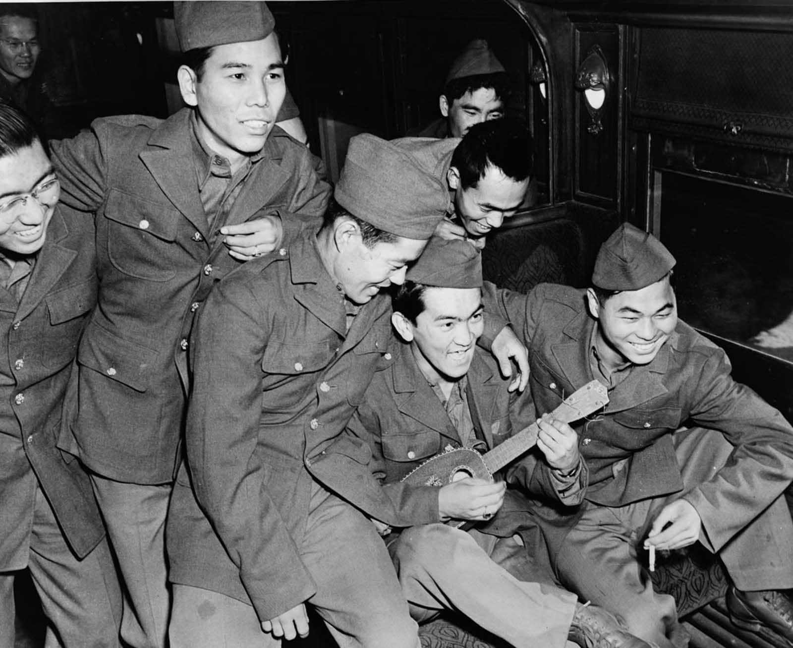 Soldiers enjoy ukulele music while awaiting orders. 1943.