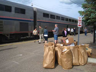 Amtrak train at the station curb, with bundles of trash bags beside it