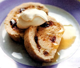 A roll of white sponge topped with sultanas and lemon zest in a brown sugar base that's rolled and sliced into rounds before serving with tea or as a pudding with custard or cream