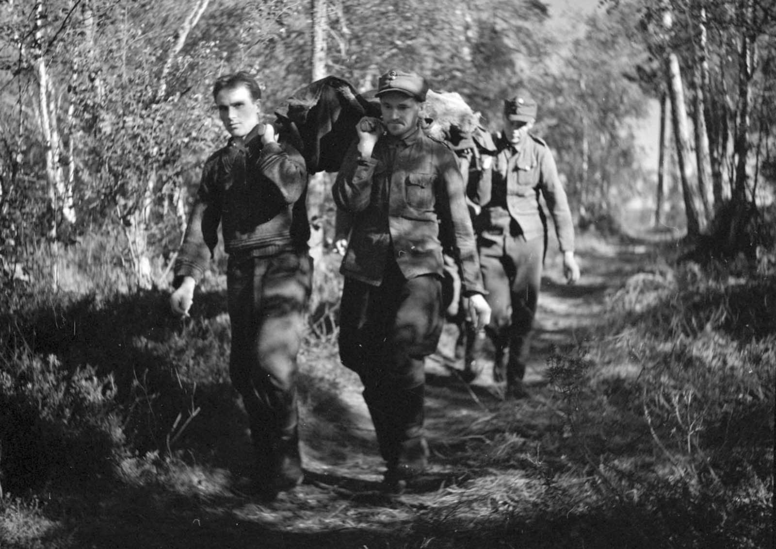 Soldiers carry a wounded man on a path.