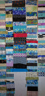 Chinese Coin strips from vintage fabrics are sewn into a quilt top