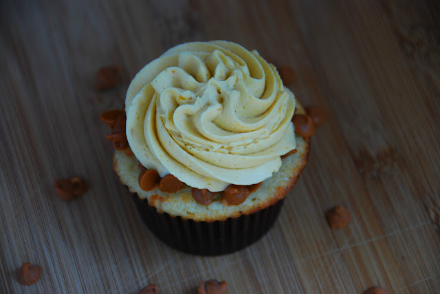 overhead close up of cupcake in brown wrapper with swirl of white icing on top