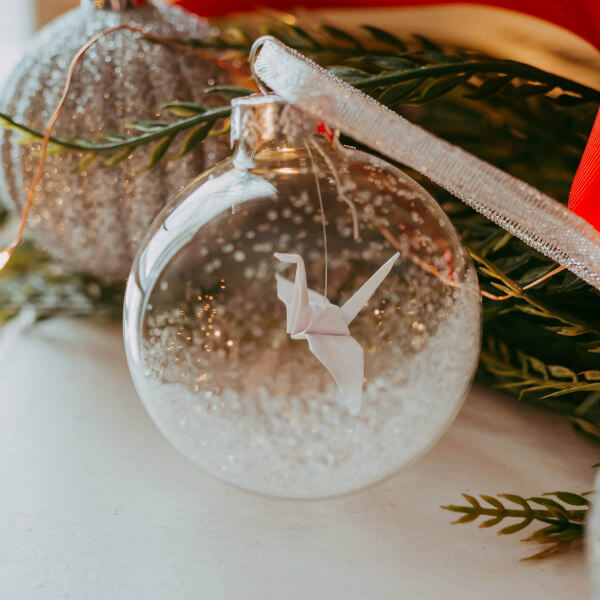 origami peace crane and glitter in a clear glass ball tree ornament