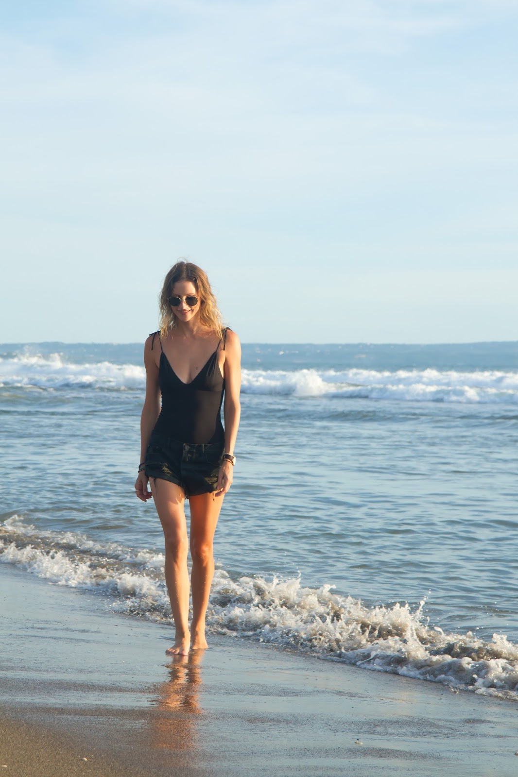 Fashion and Travel blogger, Alison Hutchinson, wearing a one-piece swimsuit at sunset