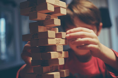 boy playing Jenga almost as tall as him