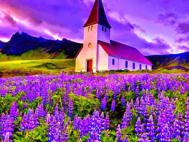 Imagen de un hermoso paisaje con un cielo en tonos violetas, montañas de fondo y mas cerca una iglesia frente a un campo de lavandas en flor