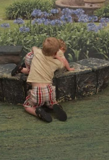 A little boy trying to bite his little brother in the back.