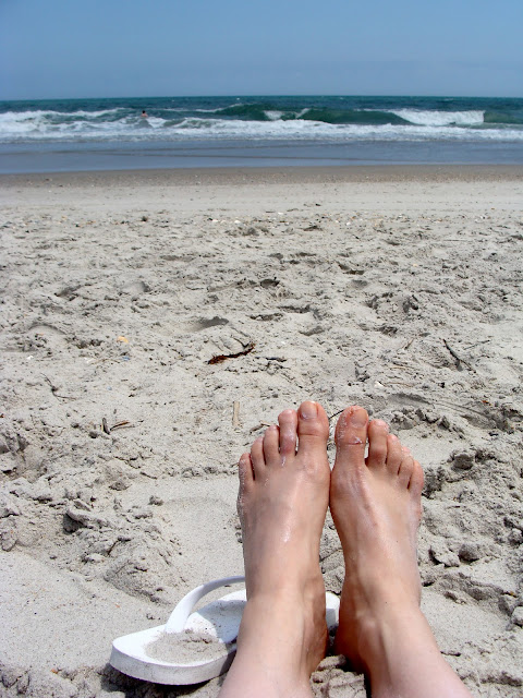 warm sandy beach with flip flops and toes in the sand