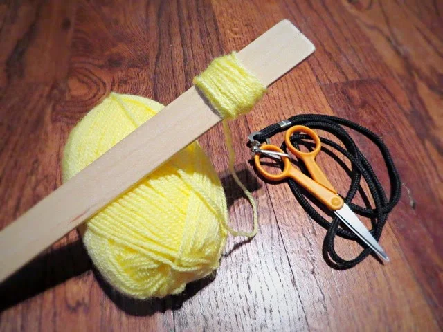 wrapping yarn around mixing stick to make pom pom