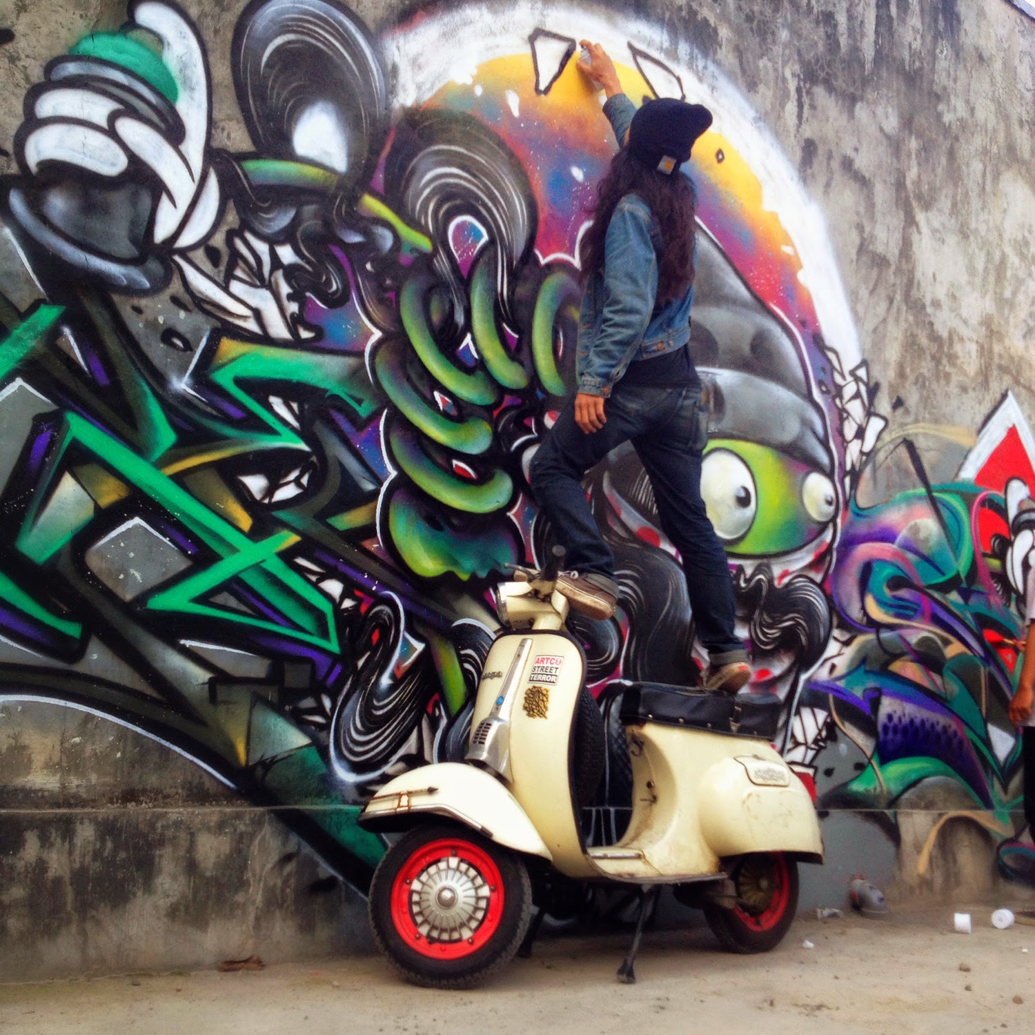 TUYULOVEME seniman graffiti senior Yogyakarta sedang beraksi diatas Vespanya