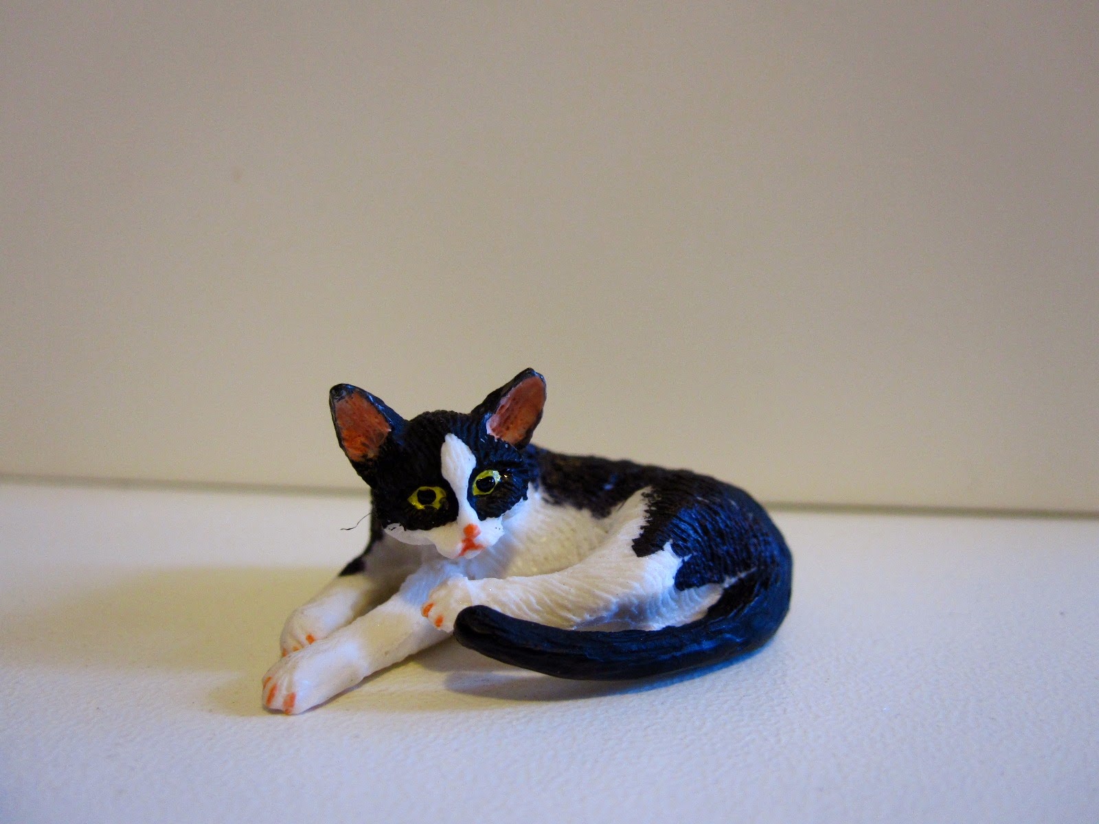 Dolls' house miniature black and white cat, lying down.