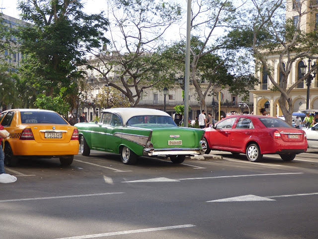 A vintage car, modern car and yellow taxi in Havana, Cuba