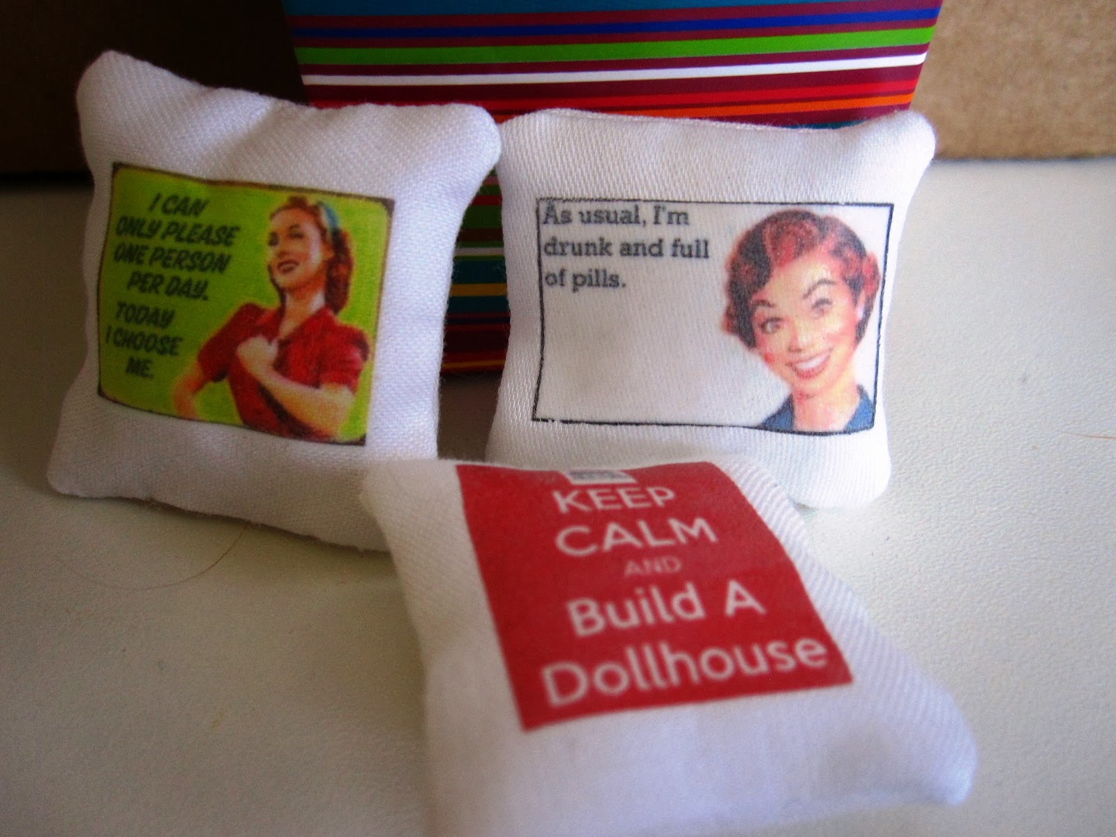 Three modern miniature cushions with funny slogans on them