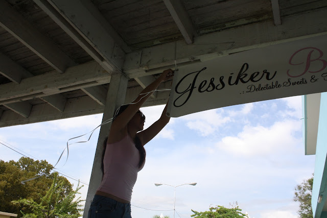 A woman putting up Jessiker bakes sign.