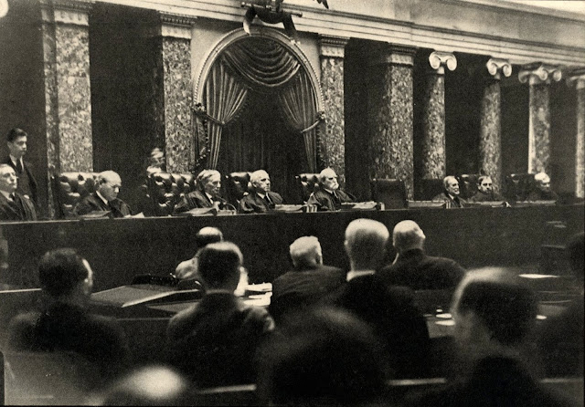 Surreptitious photograph of the Supreme Court in the Old Senate Chamber (1932) by Erich Salomon. On the bench, left to right: James McReynolds, Pierce Butler, Louis Brandeis, Willis Van Devanter, Charles Evans Hughes, George Sutherland, Owen Roberts, and Benjamin N. Cardozo. Not pictured: Harlan Fiske Stone, who would normally have occupied the empty chair.