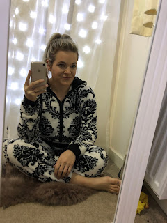 woman sitting crossed legged in mirror looking happy in white onesie