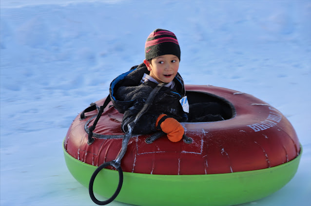 Happy boy's face riding snow tube down the hill