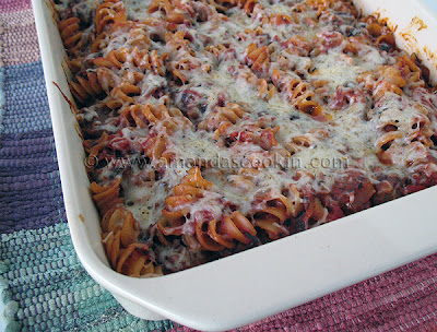 A close up photo of baked rotini with Italian sausage in a baking dish.