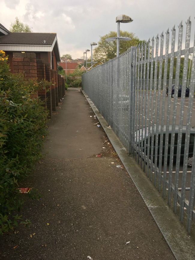 footpath-with-metal-fence-on-right-and-low-building-on-the-left